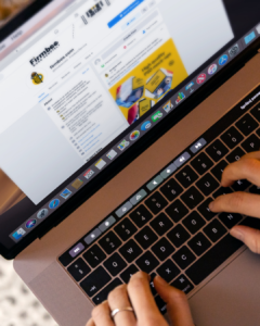 Mains tapant sur un clavier d'ordinateur portable avec un site web de communication à l'écran - quels réseaux sociaux utiliser pour une entreprise