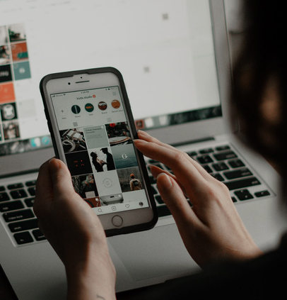 Personne gérant ses réseaux sociaux sur smartphone au-dessus d'un ordinateur portable - formation community management